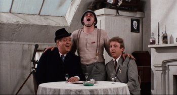 Movie still from “The Producers” (1967), directed by Mel Brooks – A group of men sitting at a table with one man standing on his shoulders; Medium shot, Low angle