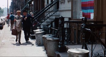 Movie still from “The Producers” (1967), directed by Mel Brooks – A man walking down the sidewalk near a fire hydrant; Wide shot, Over the shoulder angle