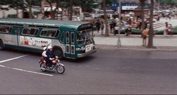 Movie still from “The Producers” (1967), directed by Mel Brooks – Two people on a motorcycle in front of a bus on a street; Extreme Wide shot, High angle