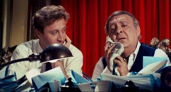 Movie still from “The Producers” (1967), directed by Mel Brooks – Two men sitting in front of a table; Medium shot, High angle