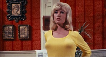 Movie still from “The Producers” (1967), directed by Mel Brooks – A woman in a yellow dress standing next to a wall; Medium shot, Low angle