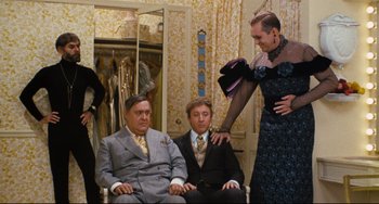 Movie still from “The Producers” (1967), directed by Mel Brooks – Three men sitting in a chair in front of a woman; Wide shot, Over the shoulder angle