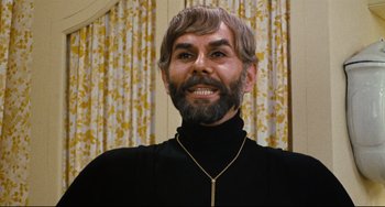 Movie still from “The Producers” (1967), directed by Mel Brooks – A man with long hair and a goatee wearing a black shirt; Close Up shot, Low angle