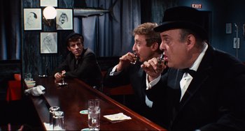 Movie still from “The Producers” (1967), directed by Mel Brooks – A group of men sitting at a table with drinks; Medium shot, Over the shoulder angle