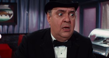 Movie still from “The Producers” (1967), directed by Mel Brooks – An older man in a black suit and a black hat; Close Up shot, Over the shoulder angle