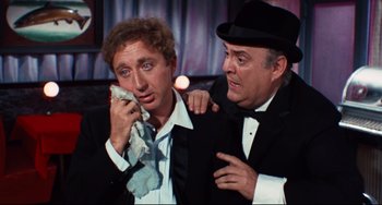Movie still from “The Producers” (1967), directed by Mel Brooks – Two men in tuxedos and hats are looking at each other; Medium shot, Low angle