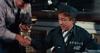 Movie still from “The Producers” (1967), directed by Mel Brooks – A man in a uniform is holding something in his hand; Medium shot, High angle