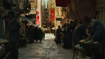 Movie still from “The Promise” (2016), directed by Terry George – A group of people walking down a street in a city; Extreme Wide shot, High angle