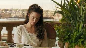 Movie still from “The Promise” (2016), directed by Terry George – A woman sitting at a table reading a book; Medium shot, Over the shoulder angle