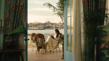 Movie still from “The Promise” (2016), directed by Terry George – A woman sitting at a table reading a book; Wide shot, High angle