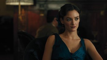 Movie still from “The Promise” (2016), directed by Terry George – A beautiful woman in a blue dress sitting in a chair; Close Up shot, Over the shoulder angle
