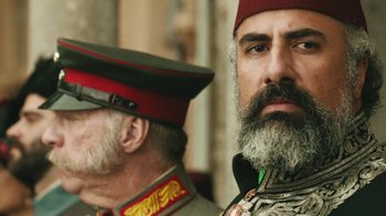 Movie still from “The Promise” (2016), directed by Terry George – A man with a beard wearing a hat and a military uniform; Close Up shot, Over the shoulder angle
