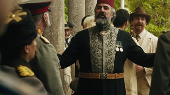 Movie still from “The Promise” (2016), directed by Terry George – A man with a beard wearing a hat; Medium shot, Over the shoulder angle