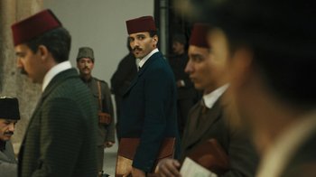 Movie still from “The Promise” (2016), directed by Terry George – A group of men standing next to each other in a room; Medium shot, Low angle