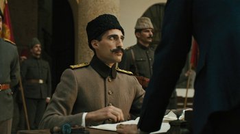 Movie still from “The Promise” (2016), directed by Terry George – A man in a military uniform sitting at a table; Medium shot, Low angle