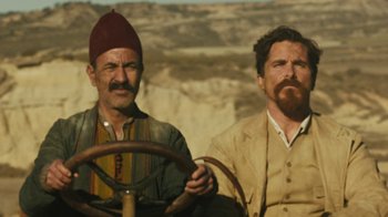 Movie still from “The Promise” (2016), directed by Terry George – Two men sitting next to each other on a dirt road; Medium shot, Low angle