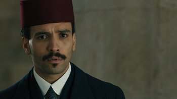 Movie still from “The Promise” (2016), directed by Terry George – A person wearing a suit and a fez; Close Up shot, High angle