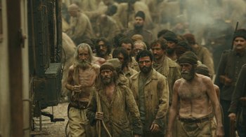 Movie still from “The Promise” (2016), directed by Terry George – A group of men standing next to each other in the dirt; Wide shot, High angle