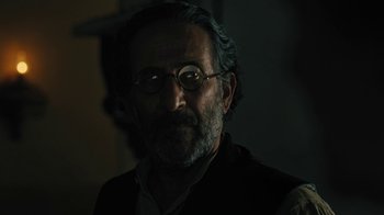Movie still from “The Promise” (2016), directed by Terry George – An older man with a beard wearing glasses; Close Up shot, Low angle