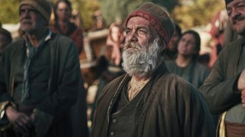 Movie still from “The Promise” (2016), directed by Terry George – An old man with a long white beard wearing a red hat; Medium shot, Over the shoulder angle