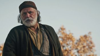Movie still from “The Promise” (2016), directed by Terry George – An old man with a beard and a hat on; Medium shot, Low angle