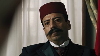 Movie still from “The Promise” (2016), directed by Terry George – A person wearing a suit and a fez; Close Up shot, Low angle