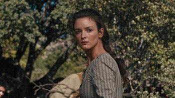 Movie still from “The Promise” (2016), directed by Terry George – A woman with long brown hair standing in front of a tree; Close Up shot, Over the shoulder angle