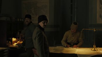 Movie still from “The Promise” (2016), directed by Terry George – A man in a military uniform standing next to a table; Medium shot, High angle