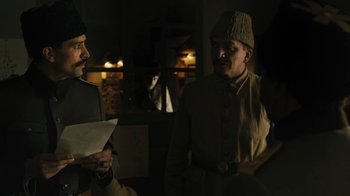 Movie still from “The Promise” (2016), directed by Terry George – Two men in military garb standing next to each other; Medium shot, Over the shoulder angle