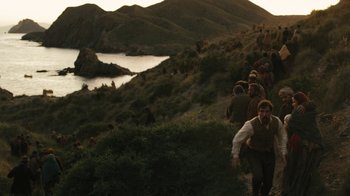 Movie still from “The Promise” (2016), directed by Terry George – A group of people walking up a hill near a body of water; Extreme Wide shot, High angle
