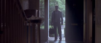 Movie still from “The Punisher” (2004), directed by Jonathan Hensleigh – A man standing in front of a door holding a bag; Wide shot, Low angle