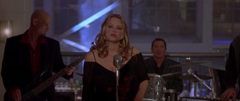 Movie still from “The Punisher” (2004), directed by Jonathan Hensleigh – A woman standing in front of a microphone in front of a band; Medium shot, Over the shoulder angle