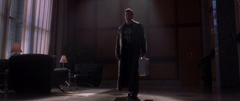 Movie still from “The Punisher” (2004), directed by Jonathan Hensleigh – A man holding a briefcase while standing on a stage; Wide shot, Low angle