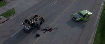Movie still from “The Punisher” (2004), directed by Jonathan Hensleigh – An accident on a city street with a car on the road and a person lying on the ground; Wide shot, Overhead angle