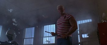 Movie still from “The Punisher” (2004), directed by Jonathan Hensleigh – A man in a red and white striped shirt holding a pair of sticks; Medium shot, Low angle