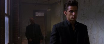 Movie still from “The Punisher” (2004), directed by Jonathan Hensleigh – A man in a suit and tie standing next to another man in a suit and tie; Medium shot, Over the shoulder angle