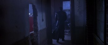 Movie still from “The Punisher” (2004), directed by Jonathan Hensleigh – A man is standing in a dark room holding a bag; Wide shot, Low angle