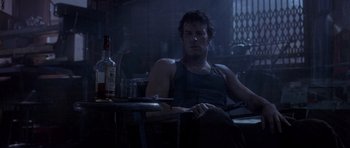Movie still from “The Punisher” (2004), directed by Jonathan Hensleigh – A man sitting at a table in a dark room; Medium shot, Low angle
