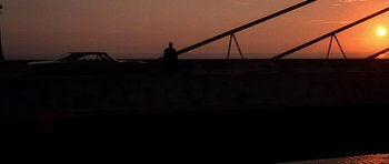 Movie still from “The Punisher” (2004), directed by Jonathan Hensleigh – A man sitting on top of a boat at sunset; Extreme Wide shot, Low angle