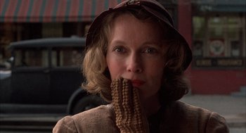 Movie still from “The Purple Rose of Cairo” (1985), directed by Woody Allen – A woman in a brown hat holding a piece of corn; Close Up shot, Low angle