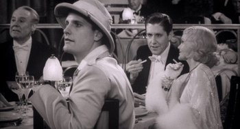 Movie still from “The Purple Rose of Cairo” (1985), directed by Woody Allen – A group of people sitting at a table with drinks; Medium shot, Over the shoulder angle