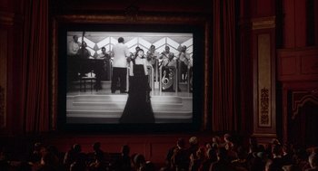 Movie still from “The Purple Rose of Cairo” (1985), directed by Woody Allen – People watching a movie in a large auditorium; Extreme Wide shot, Low angle