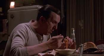 Movie still from “The Purple Rose of Cairo” (1985), directed by Woody Allen – A man sitting at a table eating food from a bowl; Close Up shot, High angle