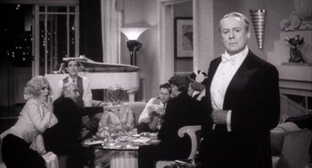 Movie still from “The Purple Rose of Cairo” (1985), directed by Woody Allen – A man in a tuxedo standing in front of a group of diners; Medium shot, Over the shoulder angle