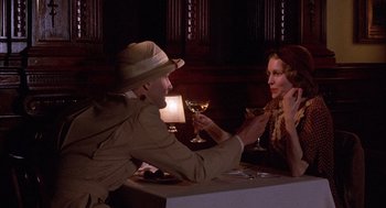 Movie still from “The Purple Rose of Cairo” (1985), directed by Woody Allen – A man and a woman sitting at a table with a glass of wine; Medium shot, Over the shoulder angle