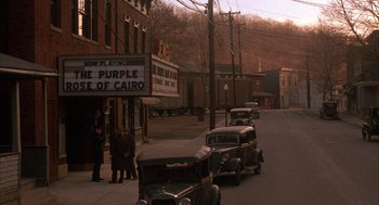 Movie still from “The Purple Rose of Cairo” (1985), directed by Woody Allen – A street scene with old cars parked on the side of the road; Extreme Wide shot, High angle
