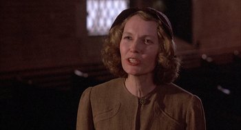 Movie still from “The Purple Rose of Cairo” (1985), directed by Woody Allen – An older woman wearing a brown coat and a hat; Close Up shot, Over the shoulder angle