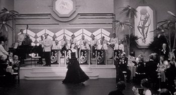 Movie still from “The Purple Rose of Cairo” (1985), directed by Woody Allen – A black and white photo of a woman in front of a group of men; Wide shot, Low angle