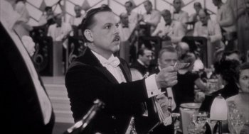 Movie still from “The Purple Rose of Cairo” (1985), directed by Woody Allen – A black and white photo of a man in a tuxedo holding money; Close Up shot, Low angle