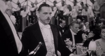 Movie still from “The Purple Rose of Cairo” (1985), directed by Woody Allen – An old photo of a man in a suit and bow tie; Close Up shot, Over the shoulder angle